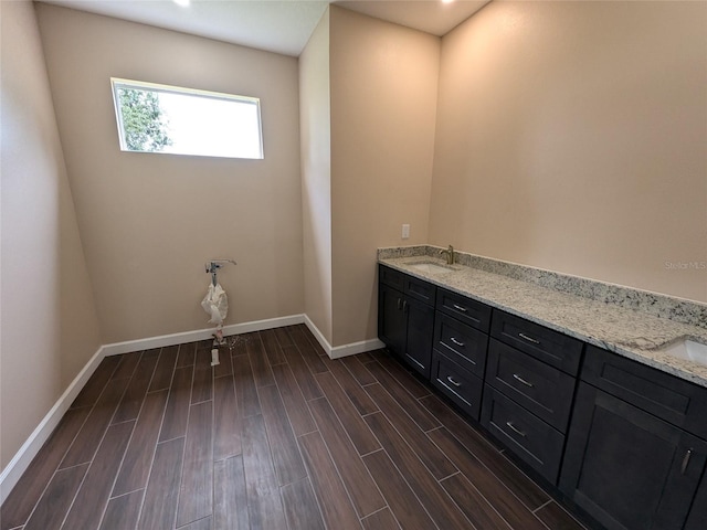 bathroom featuring a sink, baseboards, wood finish floors, and double vanity