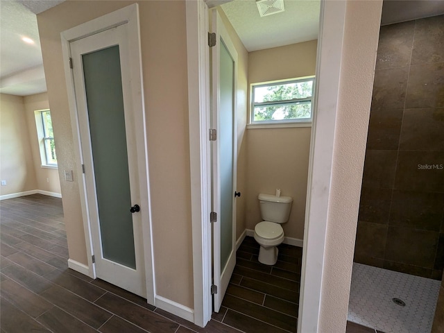 bathroom featuring a tile shower and toilet