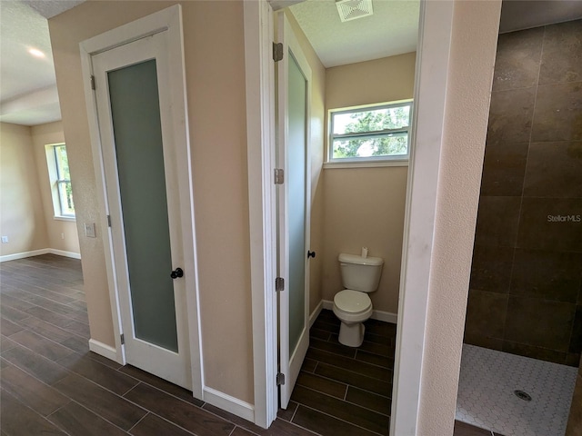 bathroom featuring wood finish floors, visible vents, toilet, and a healthy amount of sunlight