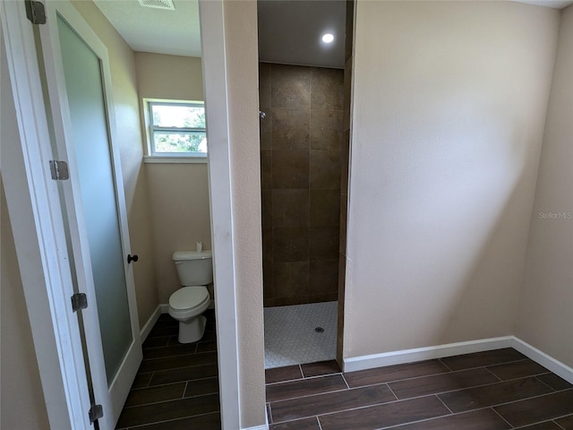 bathroom featuring a tile shower and toilet