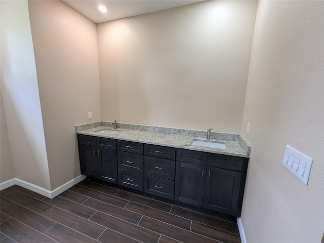full bathroom with wood tiled floor, double vanity, baseboards, and a sink