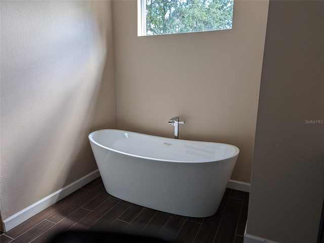 bathroom with a freestanding tub, baseboards, and wood tiled floor