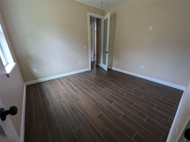 spare room with baseboards and wood finish floors