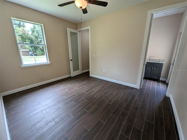 unfurnished bedroom featuring ceiling fan, ensuite bathroom, and dark hardwood / wood-style flooring