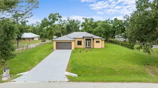 view of front of home with a garage, driveway, a front lawn, and fence