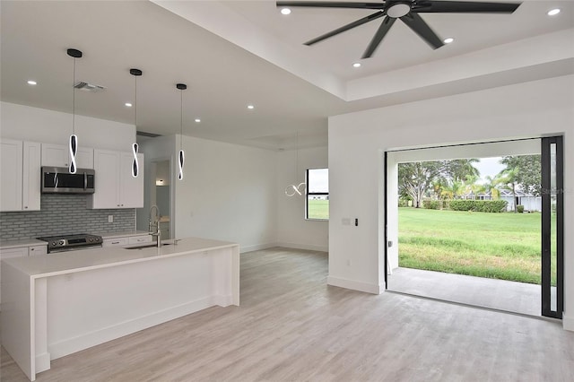 kitchen featuring white cabinetry, decorative light fixtures, light hardwood / wood-style flooring, ceiling fan, and stainless steel appliances