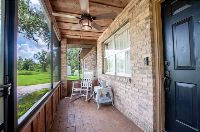 unfurnished sunroom with wood ceiling and a ceiling fan