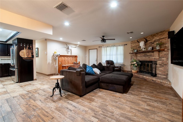 living area with light wood finished floors, a fireplace, visible vents, and recessed lighting