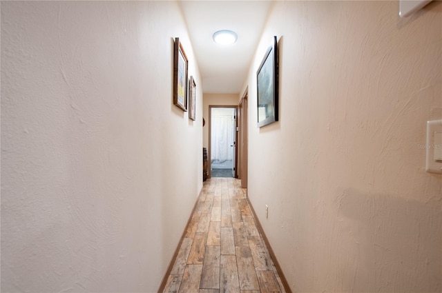 hallway with baseboards and wood finished floors