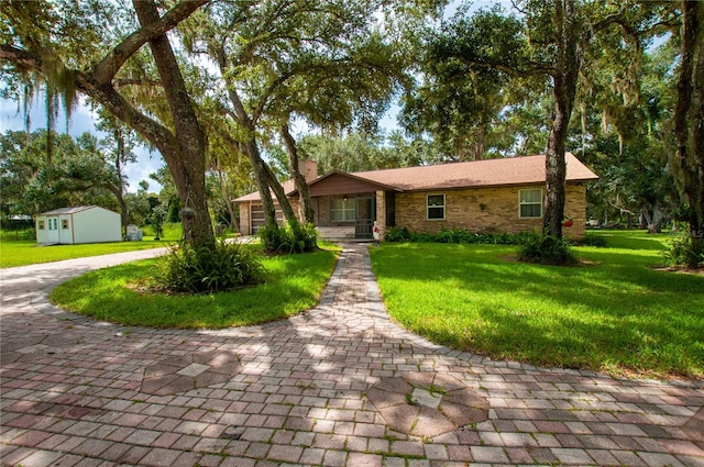 ranch-style home featuring brick siding, an outdoor structure, a chimney, and a front lawn