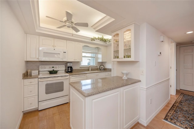 kitchen with white cabinetry, a raised ceiling, light wood-type flooring, white appliances, and ceiling fan