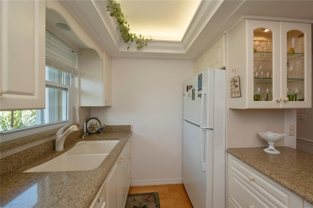 kitchen featuring sink, white cabinets, ornamental molding, and white fridge