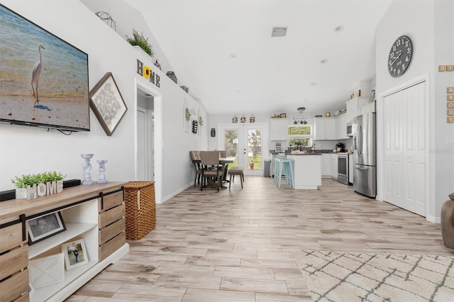 kitchen with a breakfast bar, french doors, stainless steel appliances, white cabinets, and a kitchen island