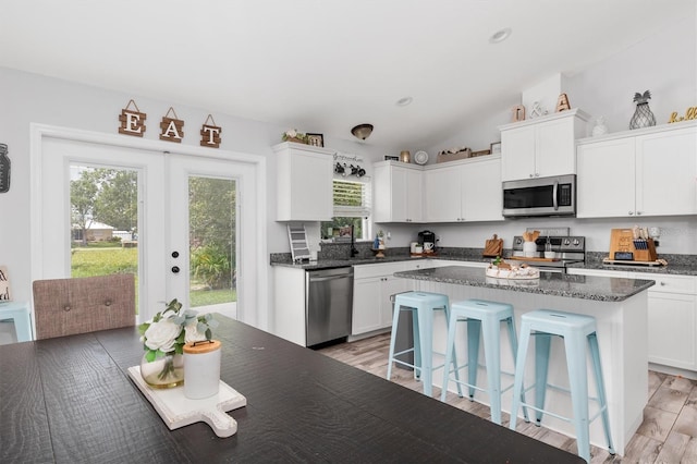 kitchen with a center island, light hardwood / wood-style flooring, appliances with stainless steel finishes, and lofted ceiling