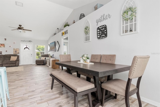 dining room with ceiling fan, vaulted ceiling, and light hardwood / wood-style floors