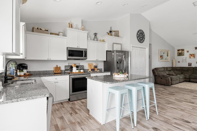 kitchen with light wood-type flooring, sink, a breakfast bar area, a center island, and stainless steel appliances