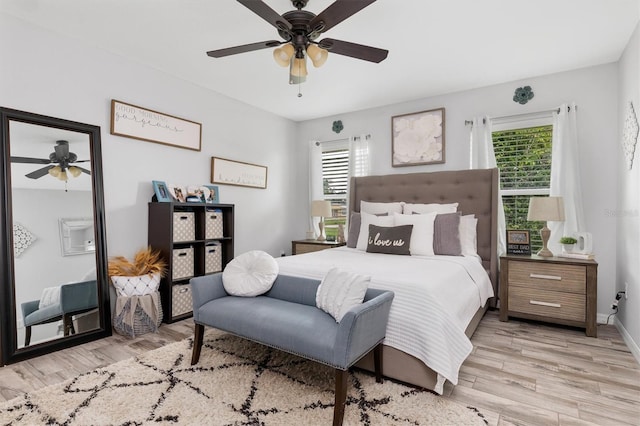 bedroom featuring ceiling fan, light wood finished floors, and multiple windows