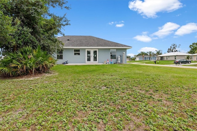 rear view of property featuring french doors and a lawn