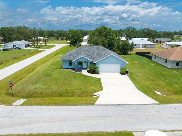 view of front of home with a front yard, concrete driveway, and an attached garage