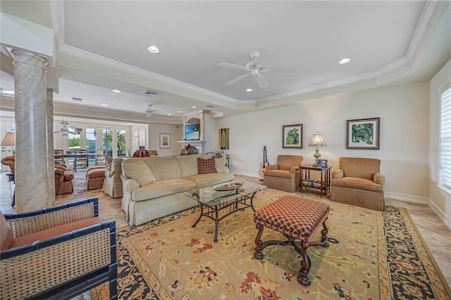 living room with ceiling fan, crown molding, a raised ceiling, and ornate columns