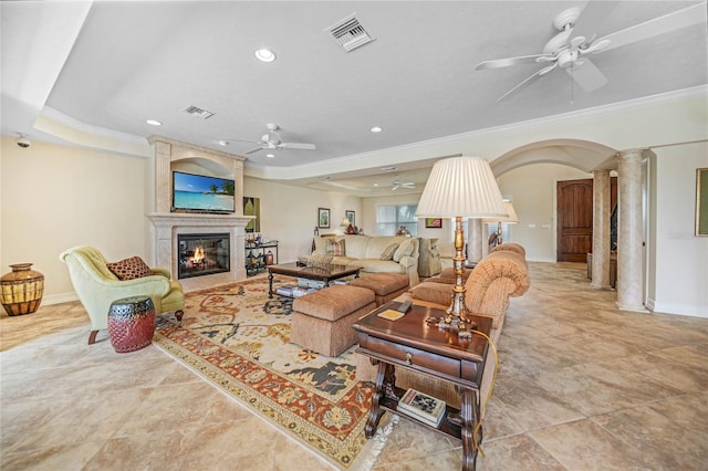 living area featuring ceiling fan, a raised ceiling, visible vents, and ornate columns