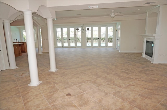 unfurnished living room featuring plenty of natural light, decorative columns, a fireplace, and ornamental molding