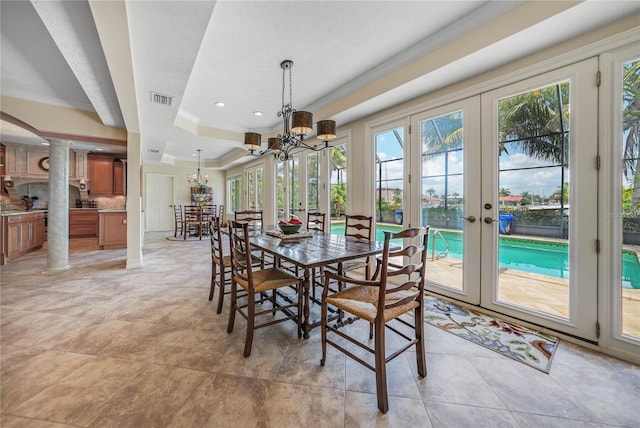 dining room with visible vents, french doors, ornate columns, a tray ceiling, and an inviting chandelier