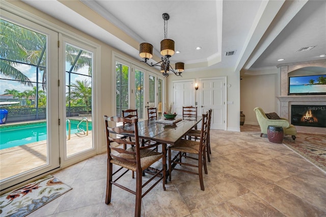 dining room with a large fireplace, a tray ceiling, visible vents, and baseboards