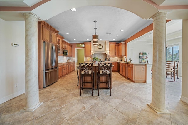 kitchen featuring stainless steel appliances, tasteful backsplash, a kitchen bar, and decorative columns