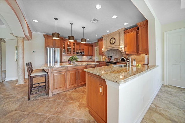 kitchen with stainless steel appliances, a peninsula, a sink, visible vents, and brown cabinetry