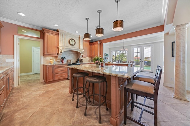 kitchen featuring stainless steel electric range oven, a breakfast bar, light stone countertops, ornate columns, and backsplash