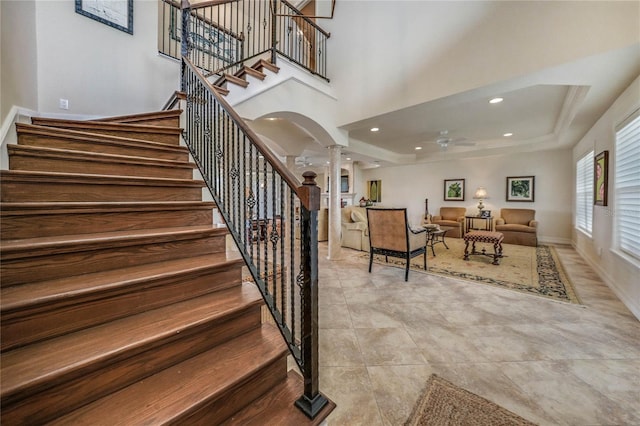 staircase featuring decorative columns, recessed lighting, a towering ceiling, a ceiling fan, and baseboards