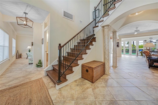 stairway with arched walkways, ceiling fan, ornamental molding, a high ceiling, and french doors