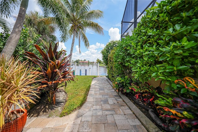 view of yard featuring a boat dock, glass enclosure, and a water view