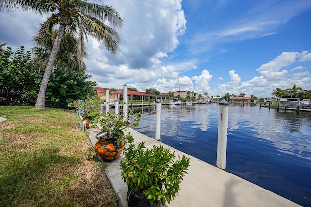 view of dock with a water view and a lawn