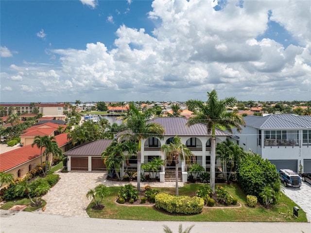 mediterranean / spanish-style home featuring a garage, a residential view, metal roof, and decorative driveway