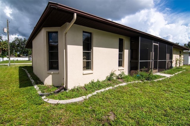 view of home's exterior featuring a sunroom and a yard