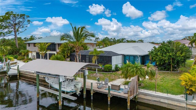 view of dock with glass enclosure, a water view, and a yard