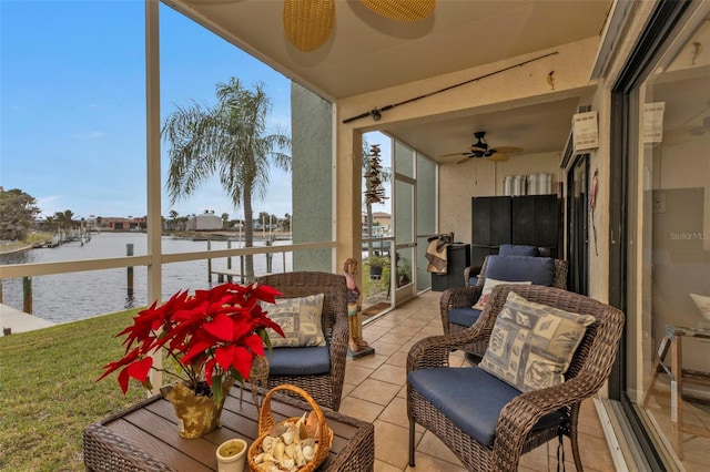 sunroom / solarium with ceiling fan and a water view