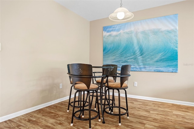 dining space featuring wood-type flooring and vaulted ceiling