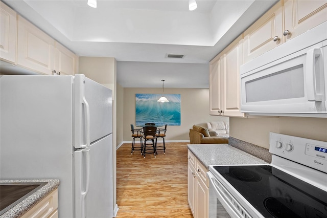 kitchen with white appliances, hanging light fixtures, and light hardwood / wood-style floors