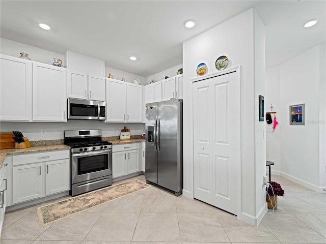 kitchen featuring light tile patterned floors, recessed lighting, appliances with stainless steel finishes, light stone countertops, and baseboards