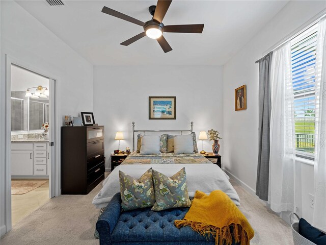 bedroom featuring ceiling fan, connected bathroom, and light carpet