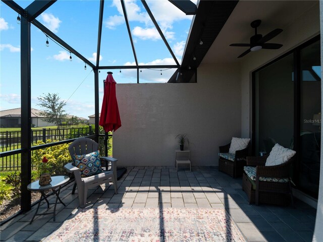 view of patio featuring a ceiling fan, a lanai, and fence