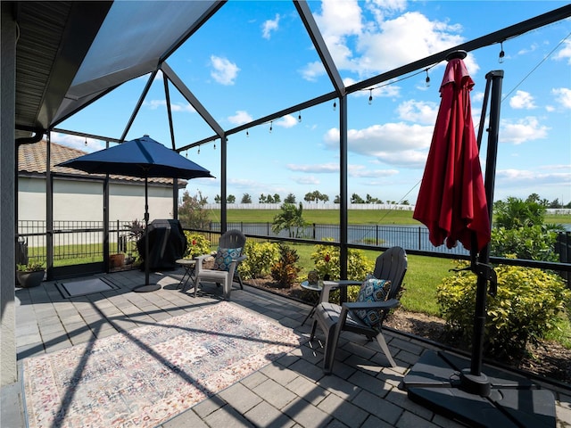 view of patio with a grill, glass enclosure, fence, and a rural view