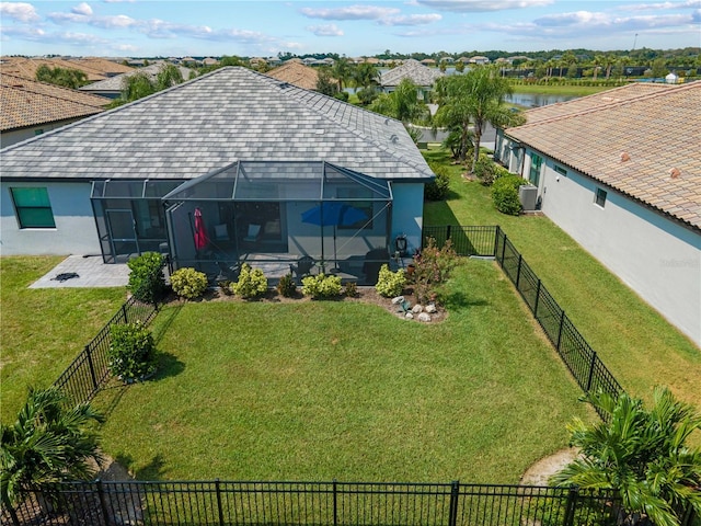 exterior space with a water view, glass enclosure, a fenced backyard, and a patio