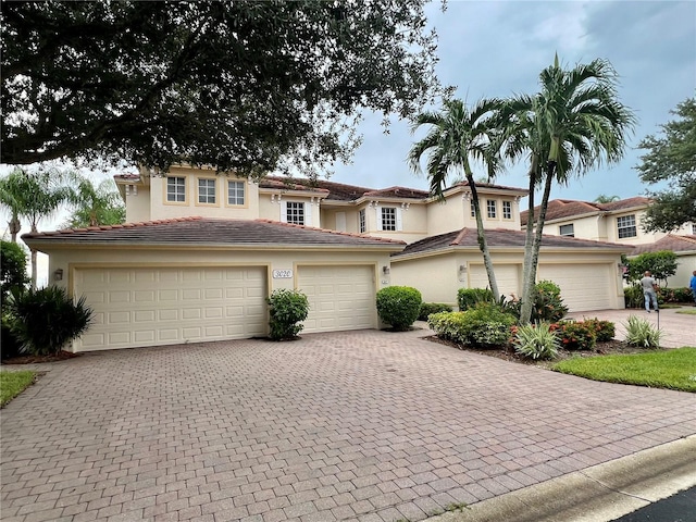 view of front facade featuring a tiled roof, decorative driveway, and stucco siding