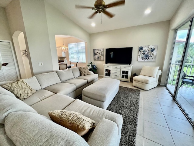 living room with light tile patterned floors, ceiling fan with notable chandelier, and high vaulted ceiling