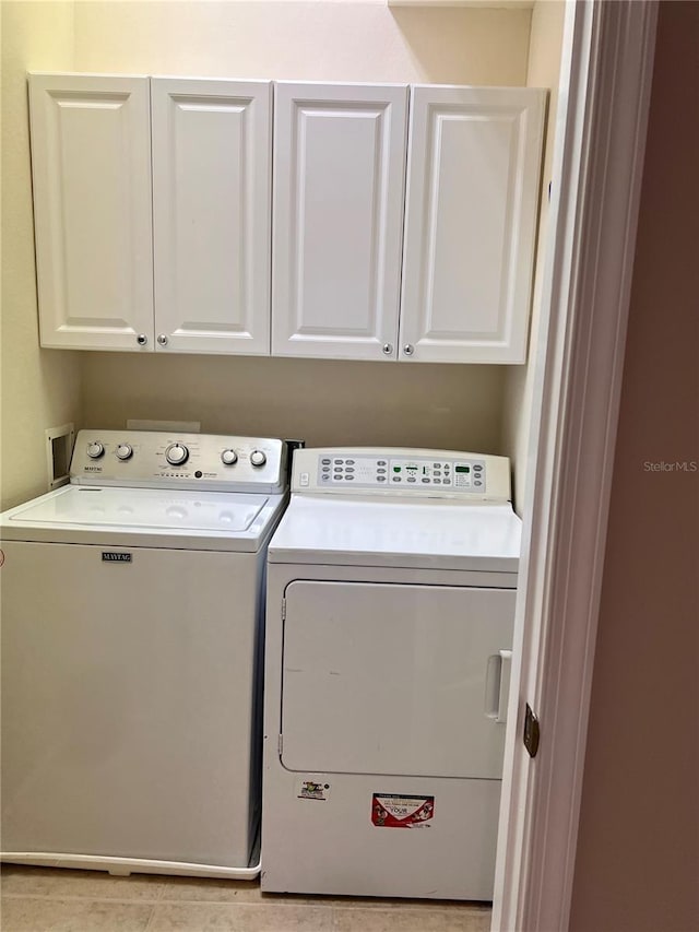 laundry area featuring light tile patterned flooring, cabinets, and independent washer and dryer