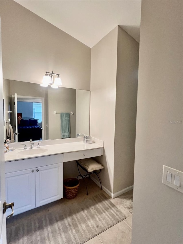 bathroom featuring lofted ceiling, tile patterned flooring, connected bathroom, vanity, and baseboards